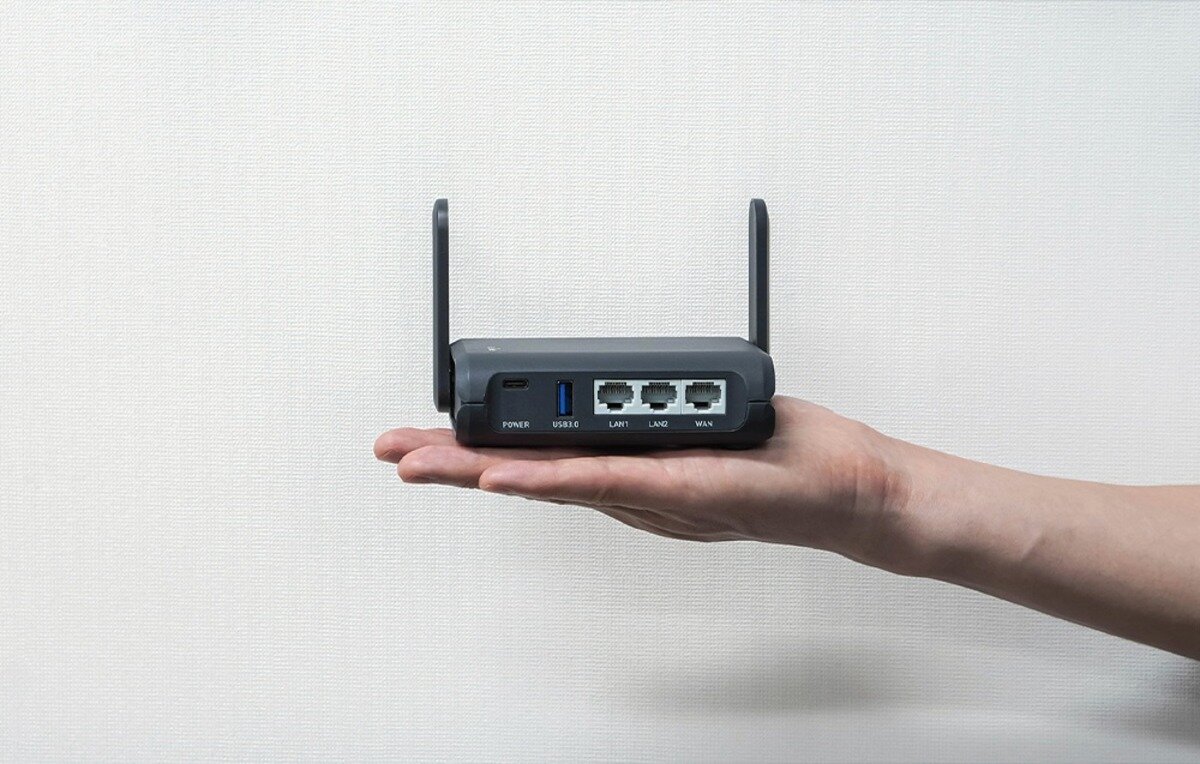 Czarny router z antenami trzymany w dłoni na jasnym tle