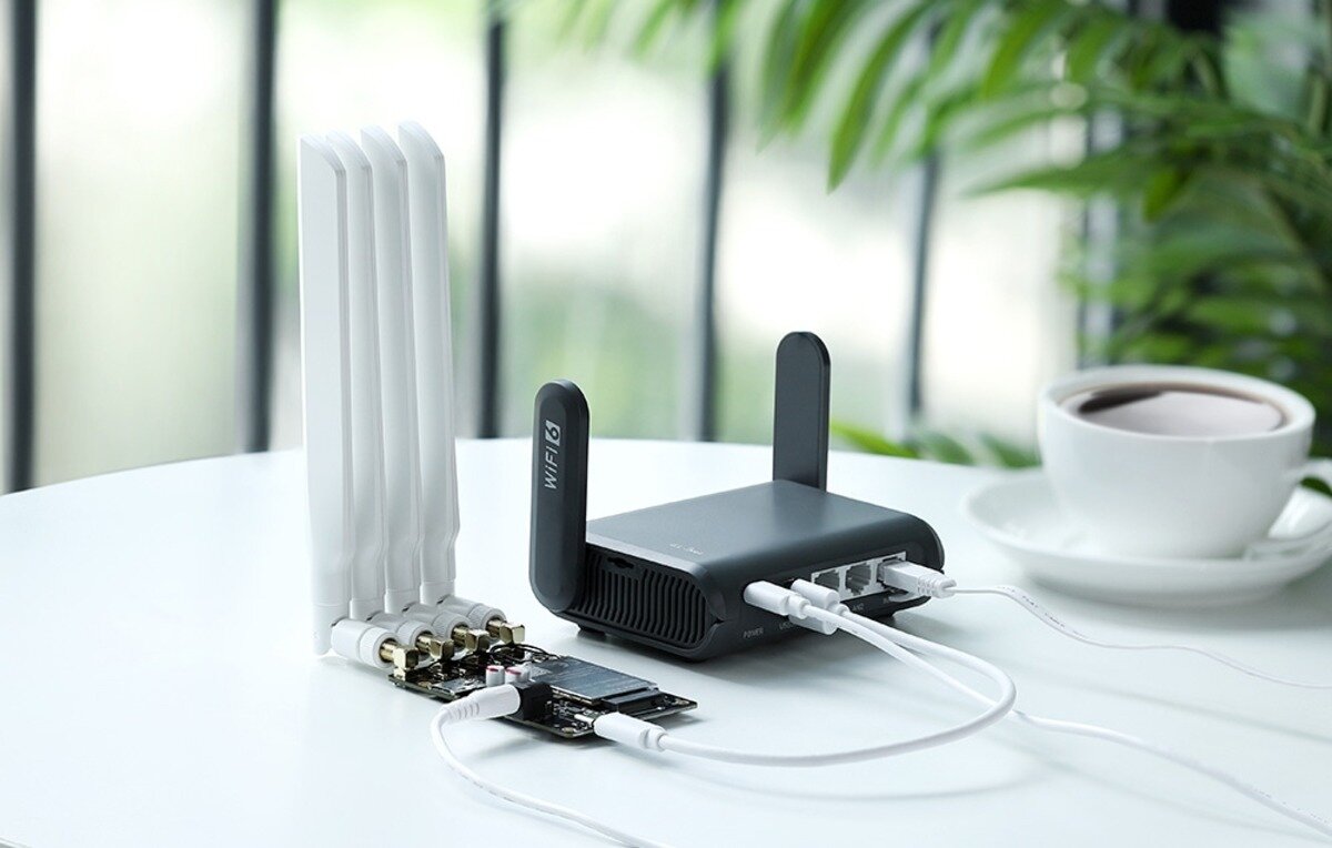 Czarny router leży na białym stoliku obok filiżanki z kawą