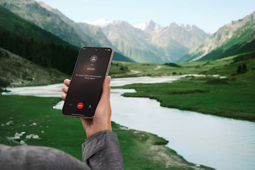 Osoba trzyma smartfon, na ekranie którego widać trwające połączenie telefoniczne z napisem \'Mr. Steve Online Communication\'. W tle rozciąga się malowniczy krajobraz z rzeką i górami.
