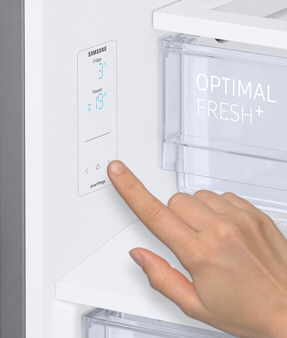 Wewnętrzny panel sterowania Panel sterowania lodówki z wyświetlaczem pokazującym temperaturę: Fridge 3°C, Freezer -18°C. Obok znajduje się przezroczysty pojemnik z napisem \'OPTIMAL FRESH+\'.