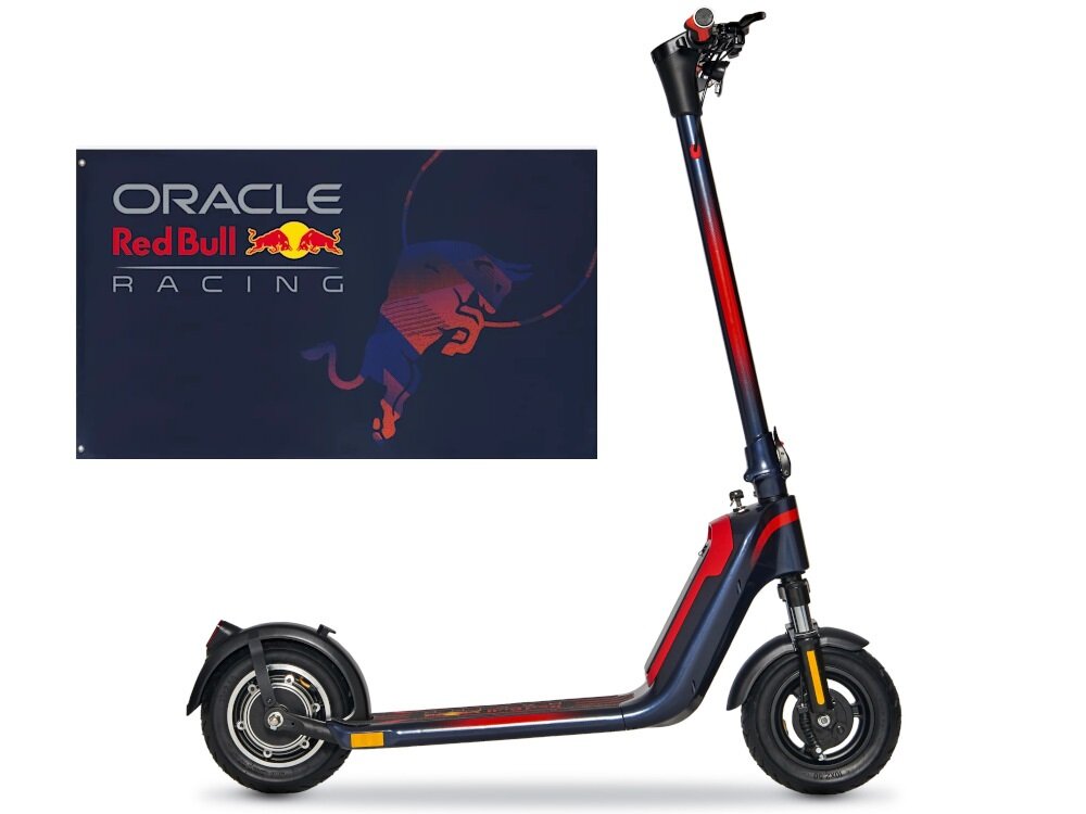 Hulajnoga elektryczna w kolorach granatowym i czerwonym z widocznym logo Red Bull. Obok znajduje się baner z napisem \'ORACLE Red Bull RACING\'.