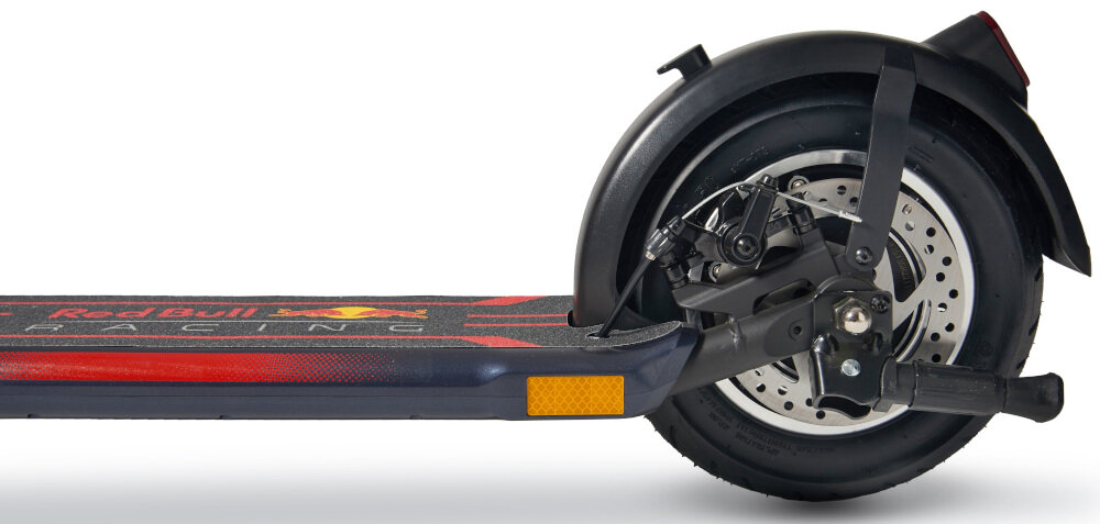 Zbliżenie na tylne koło hulajnogi elektrycznej z widocznym hamulcem tarczowym. Na podeście widoczny jest napis \'Red Bull Racing\'.