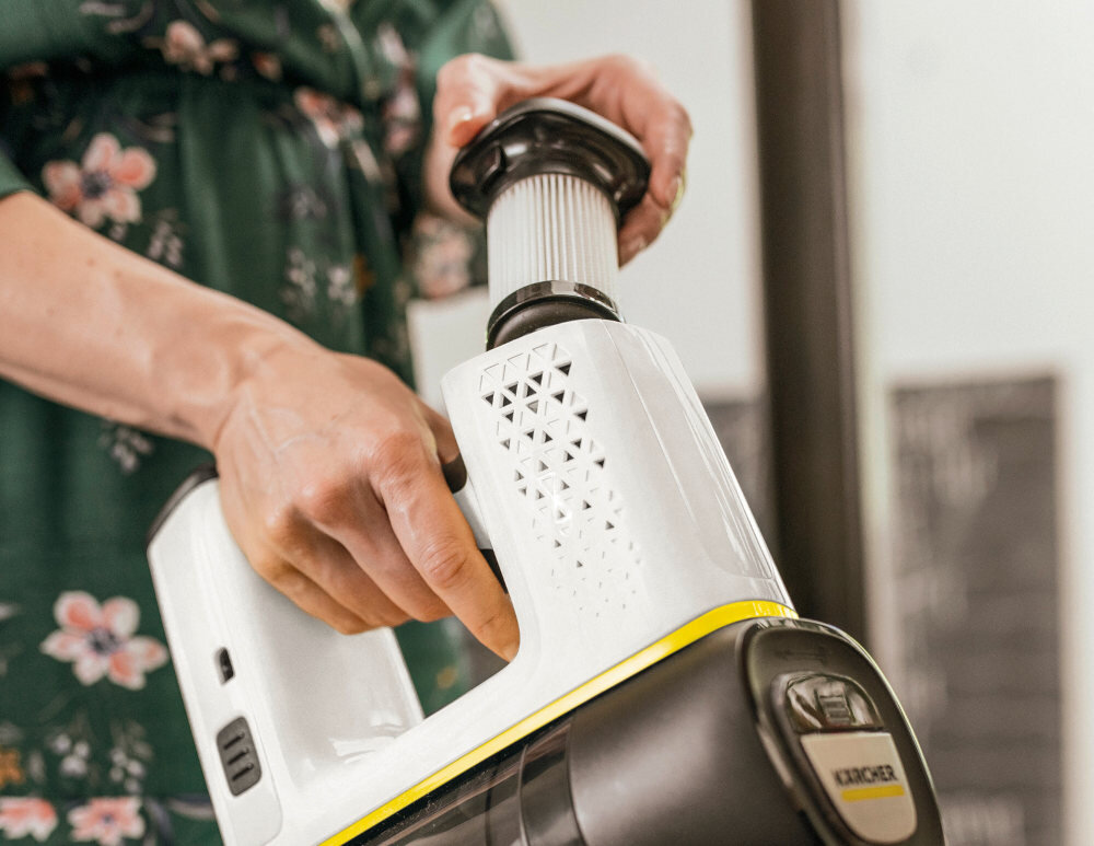 Osoba trzyma odkurzacz ręczny z widocznym filtrem i logo \'KARCHER\'.