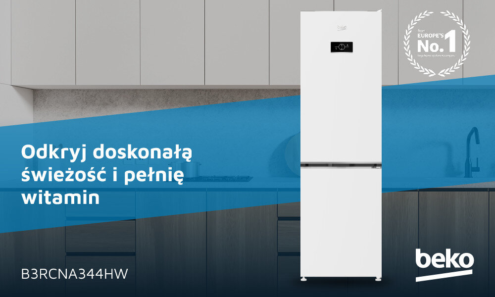 Biała lodówka z czarnym panelem na drzwiach, umieszczona na tle kuchni z szarymi szafkami. Na obrazie widoczny jest tekst: \'Odkryj doskonałą świeżość i pełnię witamin\', \'B3RCNA344HW\', oraz logo \'beko\'.