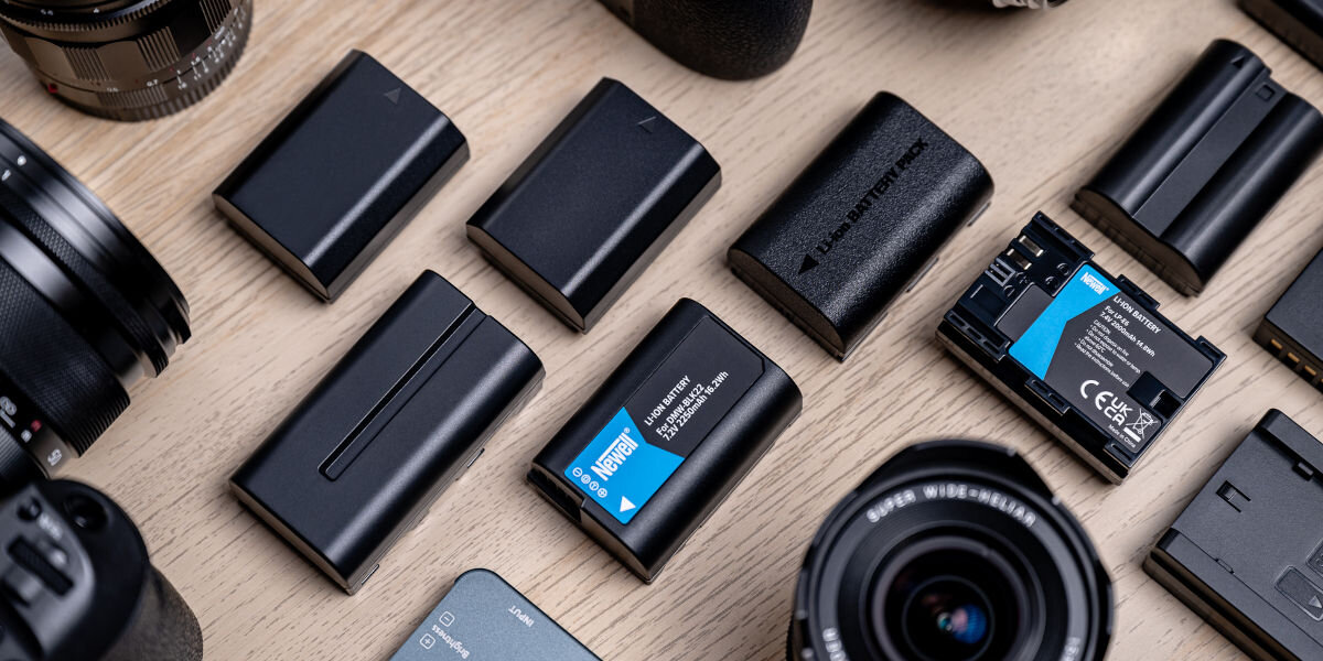 Akumulator NEWELL 1860 mAh do Pentax D-LI90, napięcie, wydajność, stabilność, bezpieczeństwo, akumulatorki stoją pionowo na pierwszym planie, w tle sprzęt fotograficzny