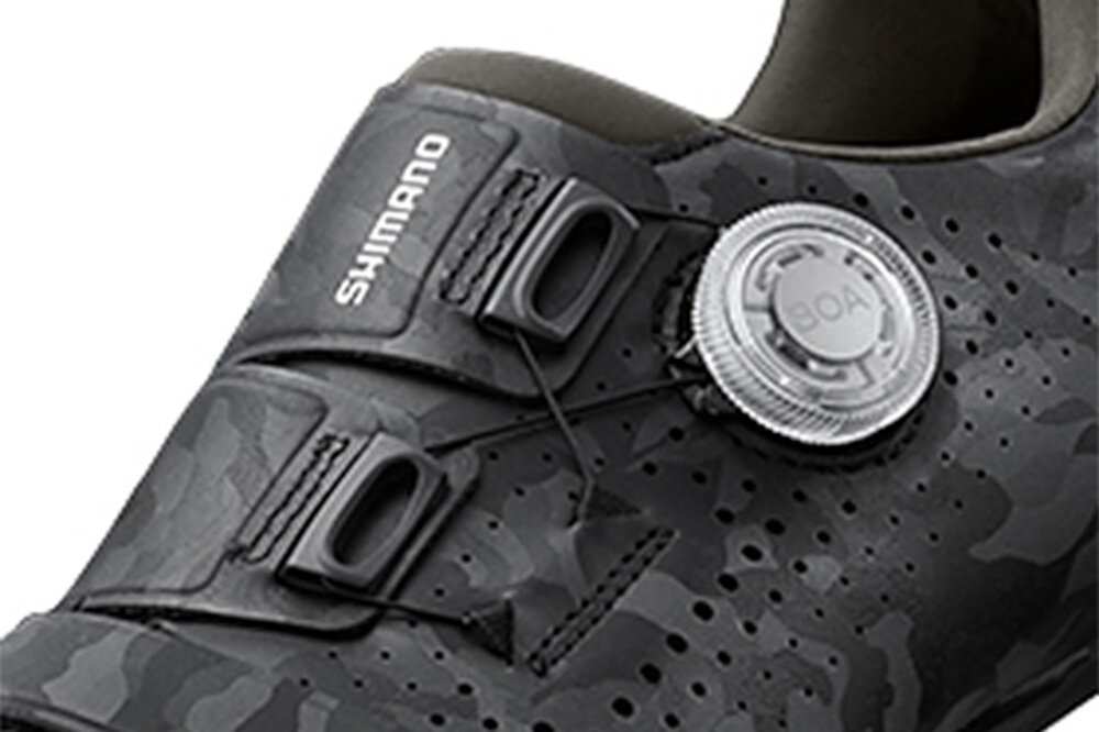 Czarny but rowerowy z widocznym logo \'SHIMANO\' oraz systemem zapięcia BOA. Powierzchnia buta ma wzór kamuflażu i perforacje.