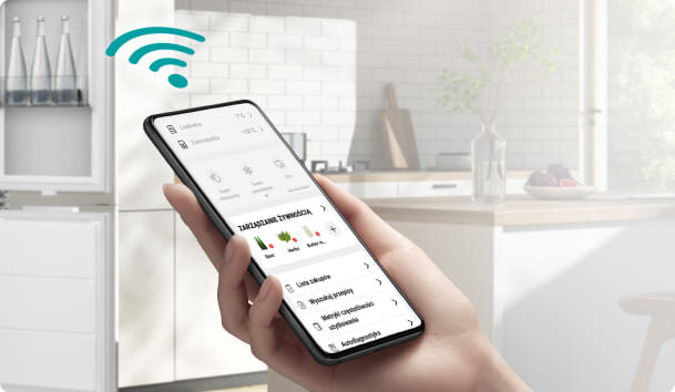 Osoba trzyma smartfon z aplikacją do zarządzania urządzeniami, w tle nowoczesna kuchnia. Na ekranie widoczny jest tekst: \'ZARZĄDZANIE URZĄDZENIAMI\'.