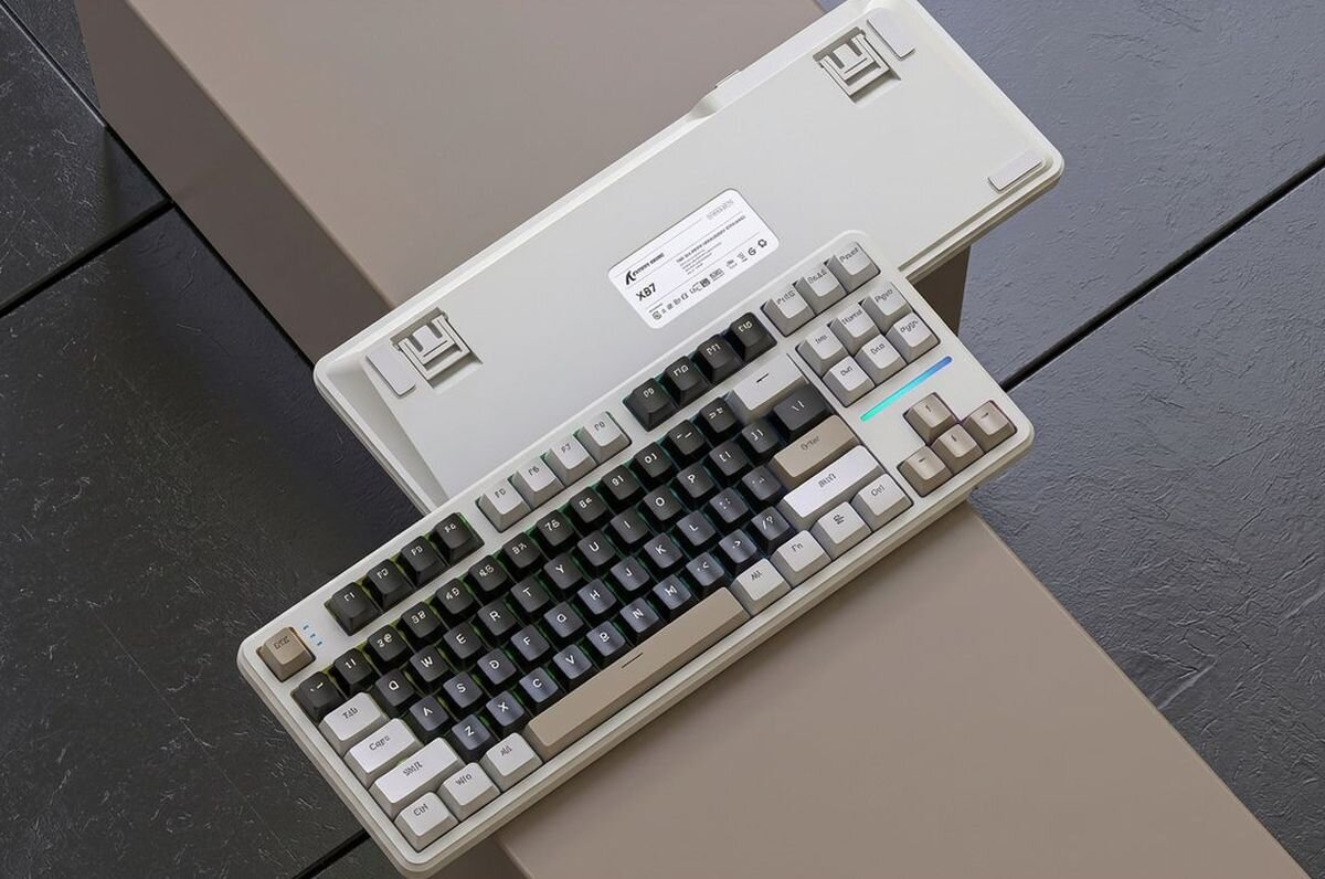 ATTACK SHARK X87 PBT (politereftalan butylenu) odpornością na ścieranie i wycieranie powierzchni błyszczących śladów profil OEM trwałość klawiszy i ich kształt - klawiatura ułożona na fioletowo-szarym tle, pokazująca spód urządzenia z nóżkami oraz górny panel