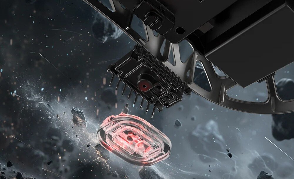 Mysz ATTACK SHARK R2 Zbliżenie na spód rozłożonej myszy. Widać złącza stykowe oraz przezroczysty element z podświetloną na czerwono cewką, wokół unoszą się drobiny pyłu