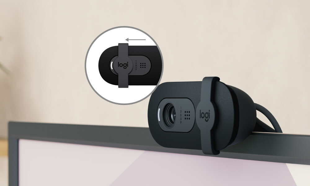Kamera internetowa w kolorze grafitowym zamontowana na monitorze, z widocznym logo \'logi\'. Obok znajduje się powiększenie pokazujące mechanizm przesuwania osłony obiektywu.