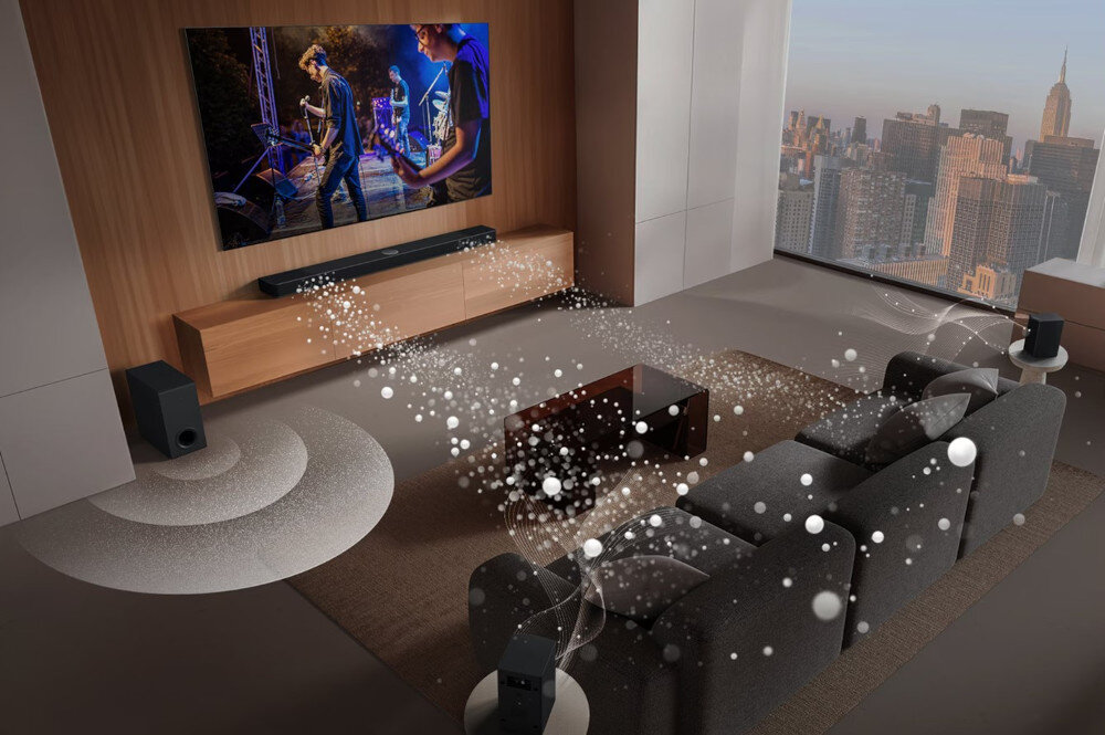 W nowoczesnym salonie znajduje się telewizor z wyświetlanym koncertem, a pod nim soundbar. Wokół rozstawione są głośniki, a przez pokój przechodzą wizualizacje dźwięku.