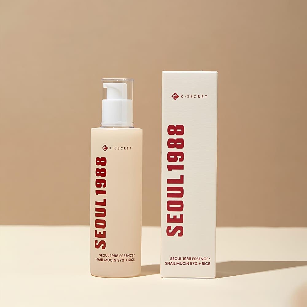 Na obrazie widoczna jest butelka z pompką oraz pudełko z napisem \'SEOUL 1988\'. Na obu znajduje się tekst \'K-SECRET\' oraz \'SEOUL 1988 ESSENCE: SNAIL MUCIN 97% + RICE\'.