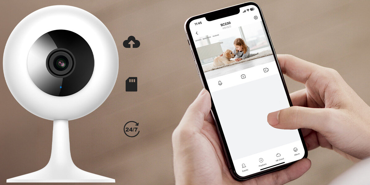 Na obrazie widoczna jest biała, obrotowa kamera wewnętrzna oraz osoba trzymająca smartfon z aplikacją pokazującą obraz z kamery. Obok kamery znajdują się ikony chmury, karty pamięci, zegara z napisem \'24/7\'.