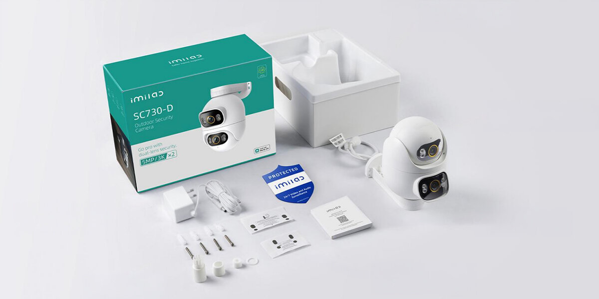 Na obrazie znajduje się kamera IP oraz jej opakowanie z napisem \'imilab SC730-D Outdoor security camera\'. Wokół kamery leżą akcesoria, takie jak kable, instrukcje i elementy montażowe.
