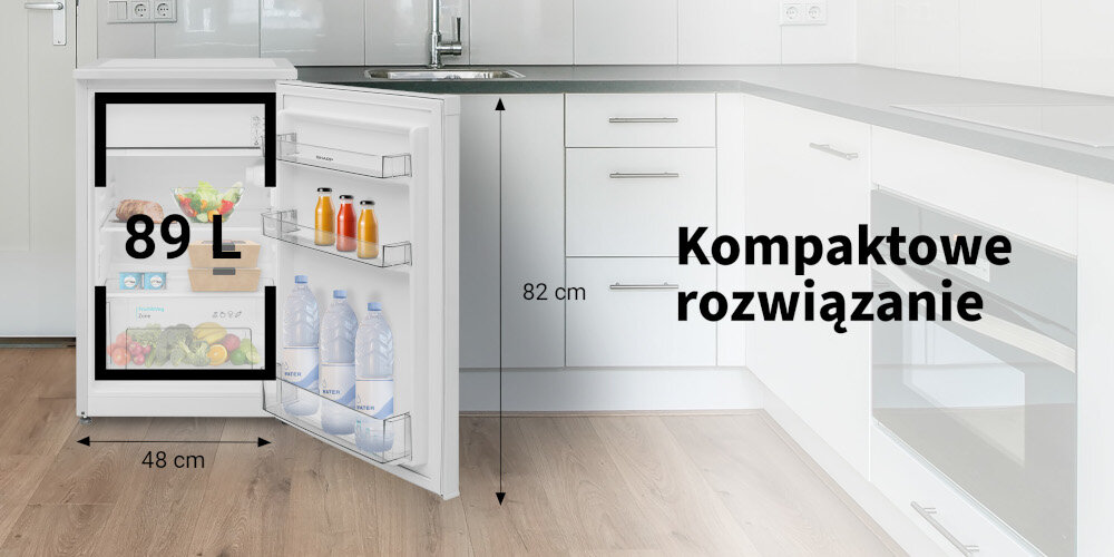 Biała lodówka o pojemności 89 L z otwartymi drzwiami, ukazująca wnętrze z napojami i produktami spożywczymi. Obok lodówki widoczny jest napis \'Kompaktowe rozwiązanie\' oraz wymiary 82 cm i 48 cm.
