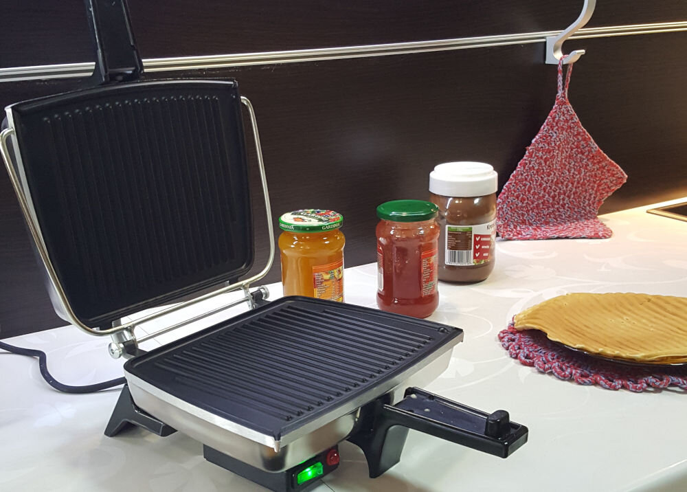 Opiekacz DEZAL Biały opiekacz stojący bokiem otwarta konstrukcja czarny środek wyżłobienia świecący włącznik obok naleśnik i różne kremy do smarowania w słoikach moc 1300 W szybkie nagrzewanie równomierne pieczenie elegancki kolor łatwe dopasowanie do różnych wnętrz spełnia swoje funkcję elegancki dodatek w każdej kuchni 