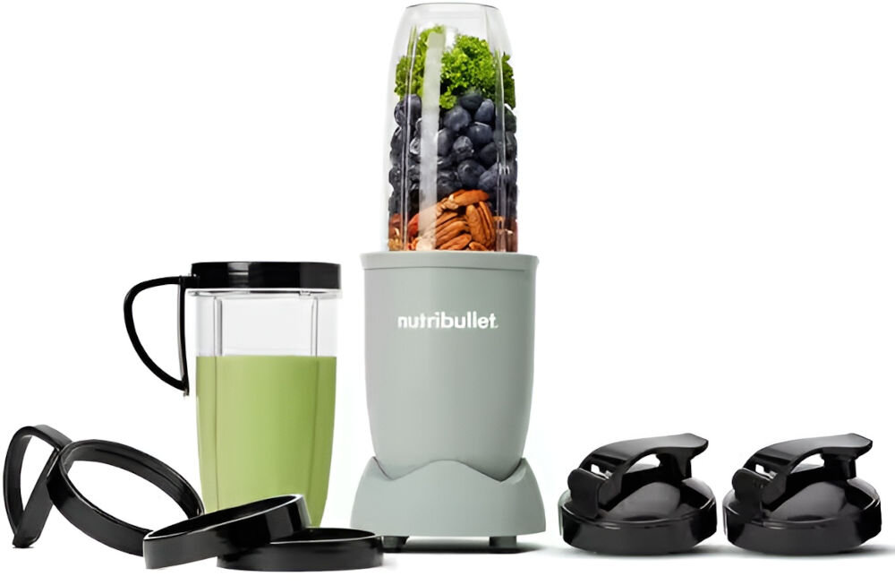 Na obrazie znajduje się blender personalny z logo \'nutribullet\', wypełniony owocami i orzechami. Obok znajdują się dodatkowe akcesoria, w tym kubek z zielonym napojem i pokrywki.