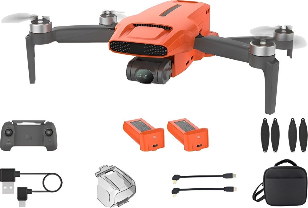 Na obrazie widoczny jest pomarańczowy dron z kamerą, rozłożonymi ramionami i śmigłami. Wokół drona znajdują się akcesoria: kontroler, dwie baterie, ładowarka, dodatkowe śmigła, kable oraz etui.