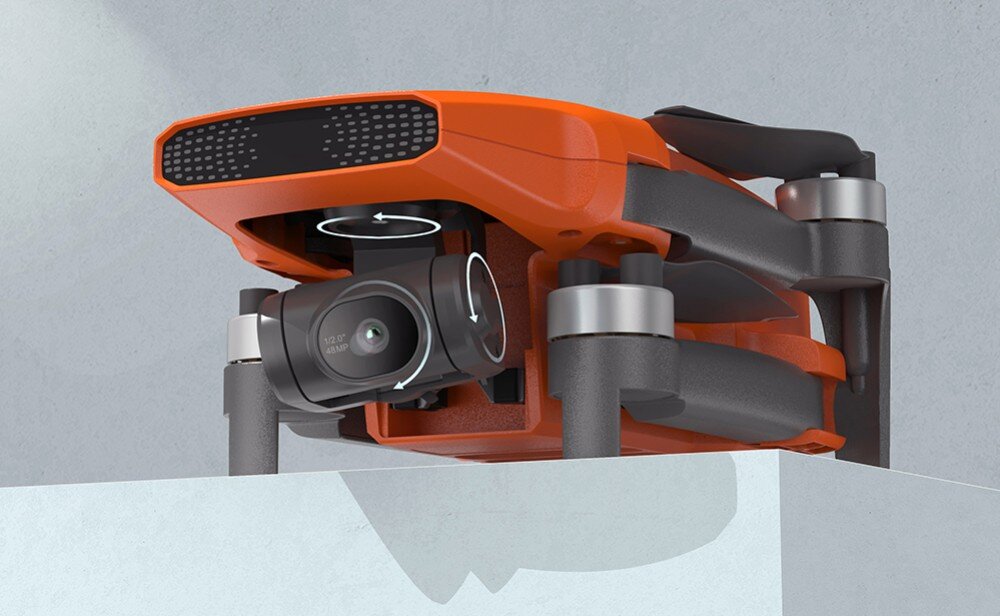 Pomarańczowy dron z widoczną kamerą i składanymi ramionami, umieszczony na jasnej powierzchni. Dron ma nowoczesny design z czarnymi elementami i metalicznymi akcentami.