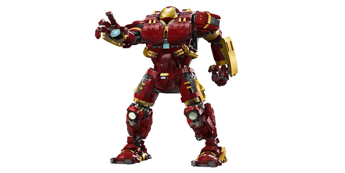 Model przedstawia dużą figurkę robota w czerwono-złotych barwach z podniesioną ręką. Robot ma szczegółowe elementy konstrukcyjne i przypomina postać z filmu science fiction.