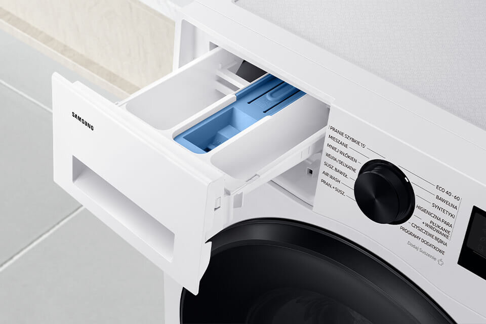 wd90dg5b15beeo z szufladą stayclean Obraz przedstawia otwarty dozownik na detergenty w pralko-suszarce z widocznym logo \'SAMSUNG\'. Na panelu sterowania widoczne są napisy: \'PRANIE SZYBKIE 15\', \'MIESZANE\', \'WEŁNA\', \'WIROWANIE\', \'HIGIENICZNE PŁUKANIE\', \'SUSZ-BEZ WIROWANIA\', \'AIR WASH\', \'PRAL+SUSZ\', \'ECO 40-60\', \'BAWEŁNA\', \'SYNTETYKI\', \'FUL PARA\', \'HIGIENICZNE PRANIE\', \'CZYSZCZENIE BĘBNA\', \'PROGRAMY DO POBRANIA\'.