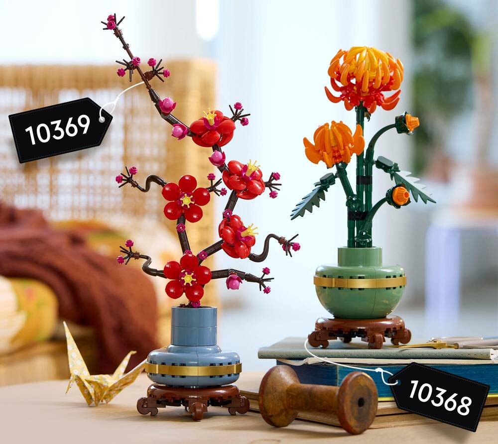 Na obrazie znajdują się dwa zestawy LEGO przedstawiające kwiaty w doniczkach, z numerami 10369 i 10368. Kwiaty mają czerwone i pomarańczowe elementy, a doniczki są ozdobione detalami w kolorze niebieskim i zielonym.