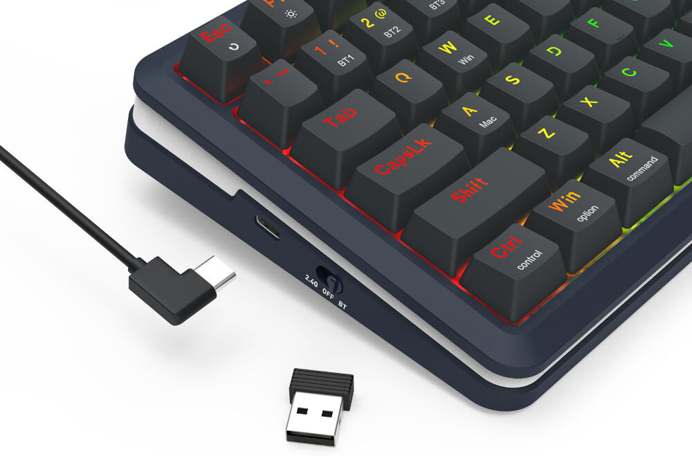 Na obrazie widoczna jest klawiatura z kolorowymi klawiszami, obok której znajduje się kabel USB oraz mały adapter USB. Klawisze mają różne kolory napisów, a na obudowie klawiatury widoczny jest przełącznik z oznaczeniami \'2.4G\', \'OFF\', \'BT\'.