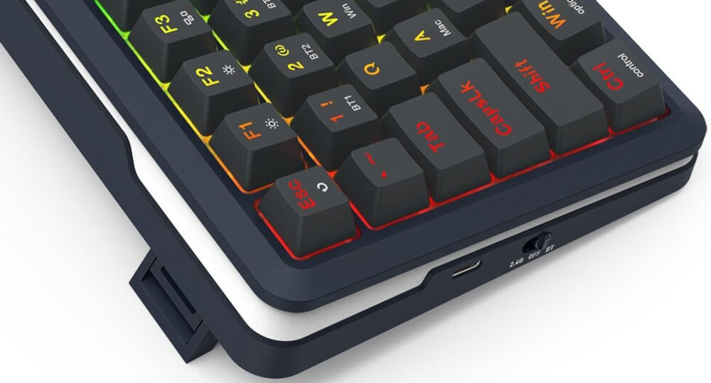 Fragment klawiatury z podświetlanymi klawiszami w różnych kolorach, w tym czerwonym i żółtym. Widoczny jest port USB oraz przełącznik z oznaczeniem \'2.4G\'.
