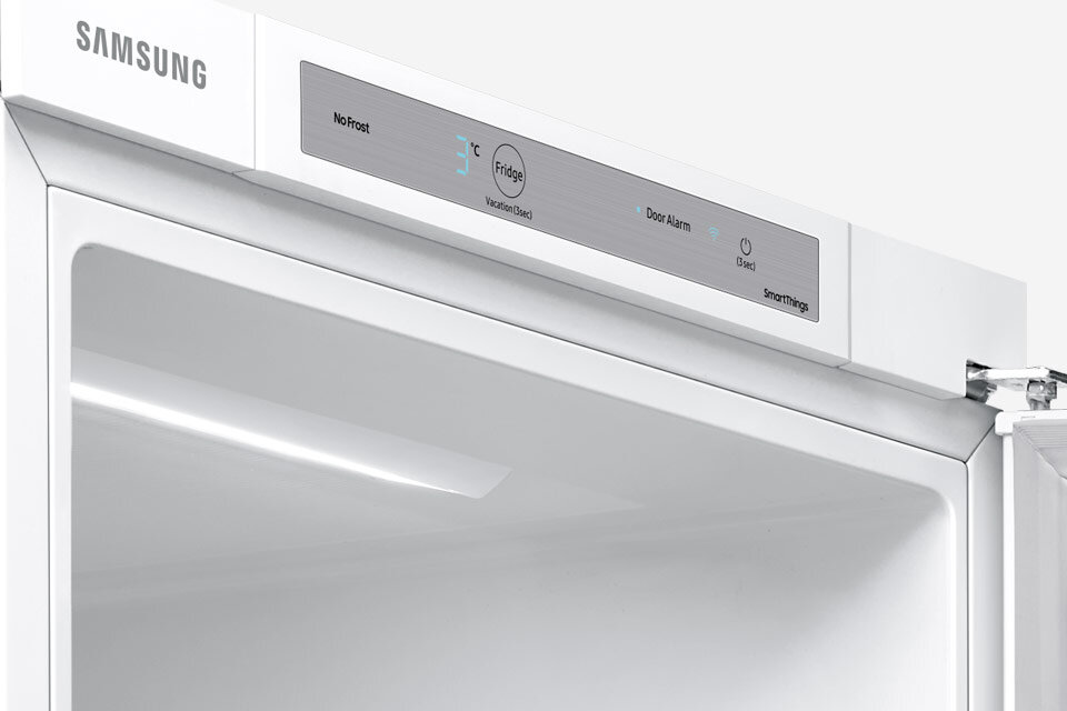 Biała lodówka z panelem sterowania, na którym widoczne są napisy: \'No Frost\', \'3°C\', \'Fridge\', \'Vacation (Hold 3 sec)\', \'Door Alarm\', \'SmartThings\'.