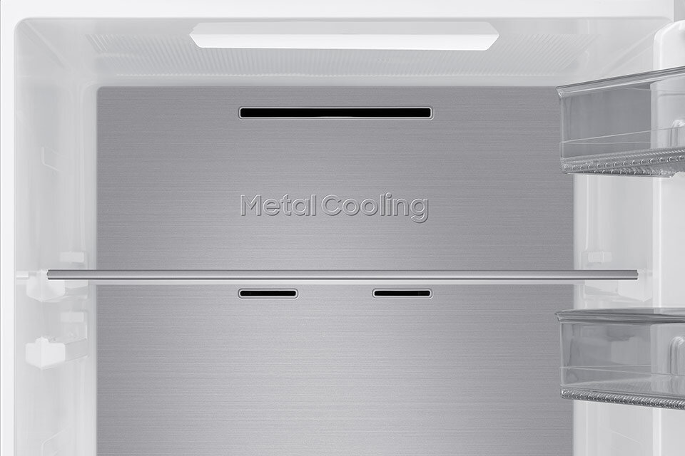Wnętrze lodówki z metalowym panelem z napisem \'Metal Cooling\'. Widoczne są przezroczyste półki i otwory wentylacyjne.