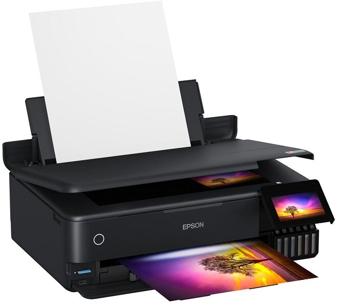 Czarne urządzenie wielofunkcyjne z logo EPSON, z wyświetlaczem i podajnikiem papieru. Widać wydrukowany kolorowy obrazek z drzewem i zachodem słońca.
