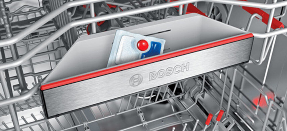 Wnętrze zmywarki z widocznym trzecim koszem ExtraSpace, w którym znajduje się tabletka do zmywania. Na koszu widnieje logo \'BOSCH\'.