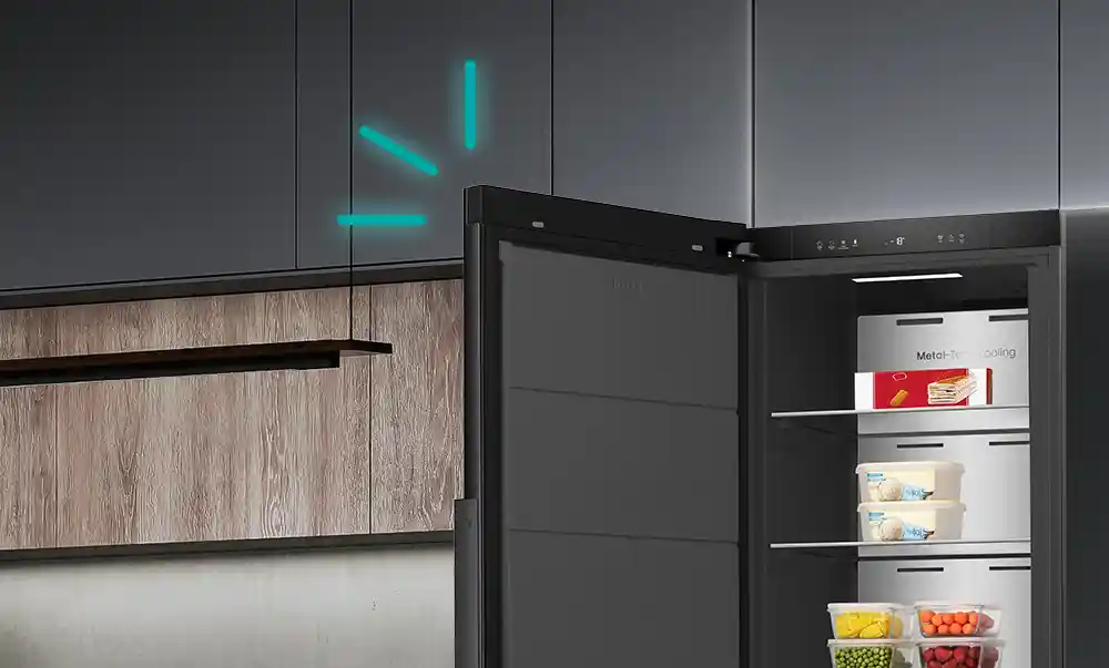 Otwarta czarna zamrażarka z widocznymi półkami, na których znajdują się różne produkty spożywcze. Na tylnej ścianie widoczny jest napis \'Metal-Tech Cooling\'.