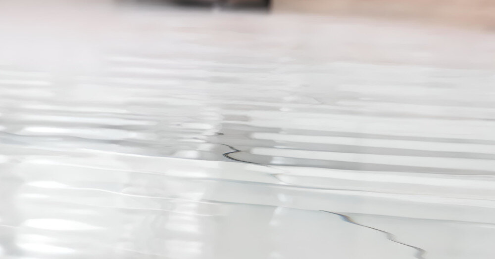 Obraz przedstawia zbliżenie na powierzchnię z widocznymi smugami wody. Tło jest rozmyte, co sugeruje, że zdjęcie skupia się na teksturze powierzchni.