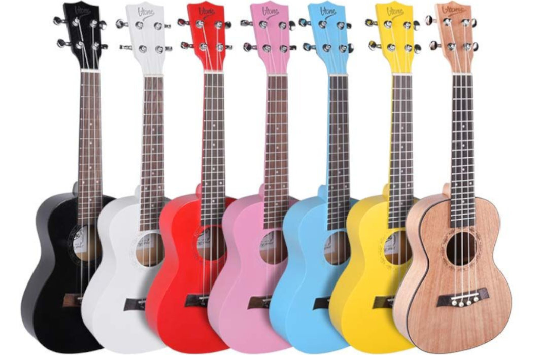 Na obrazie znajduje się osiem ukulele w różnych kolorach: czarnym, białym, czerwonym, różowym, niebieskim, żółtym i naturalnym drewnie. Każde ukulele ma logo \'V-TONE\' na główce.