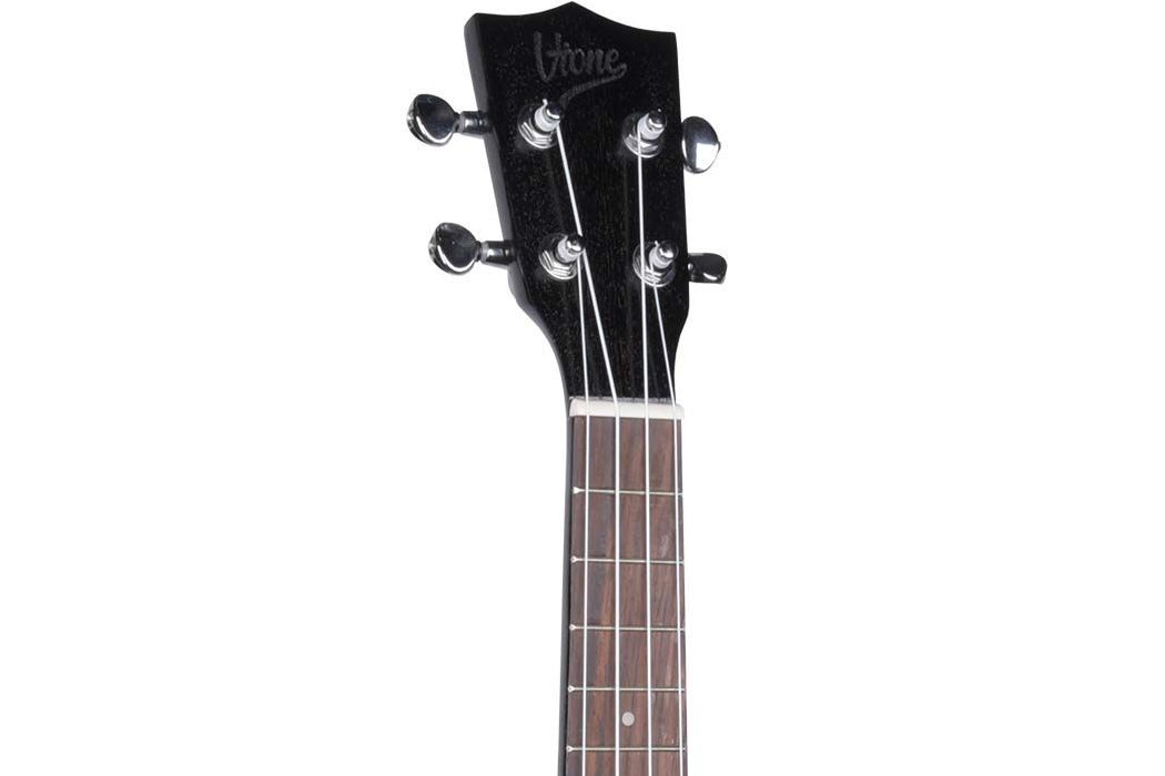 Na obrazie widoczna jest główka czarnego ukulele z logo \'V-TONE\' oraz fragment gryfu z metalowymi strunami i progami.