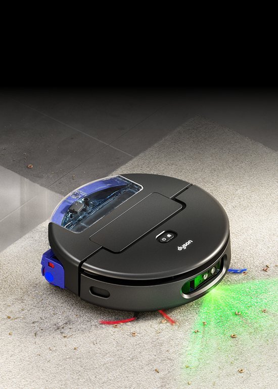 Na obrazie widoczny jest czarny robot sprzątający z logo \'dyson\', poruszający się po dywanie z rozsypanymi drobinkami. Robot emituje zielone światło na podłogę.