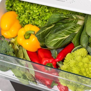 Wnętrze lodówki z szufladą wypełnioną różnymi warzywami, takimi jak papryki, sałata, brokuły i kapusta. Na szufladzie widoczny jest napis \'Fruit & Vegetable\'.