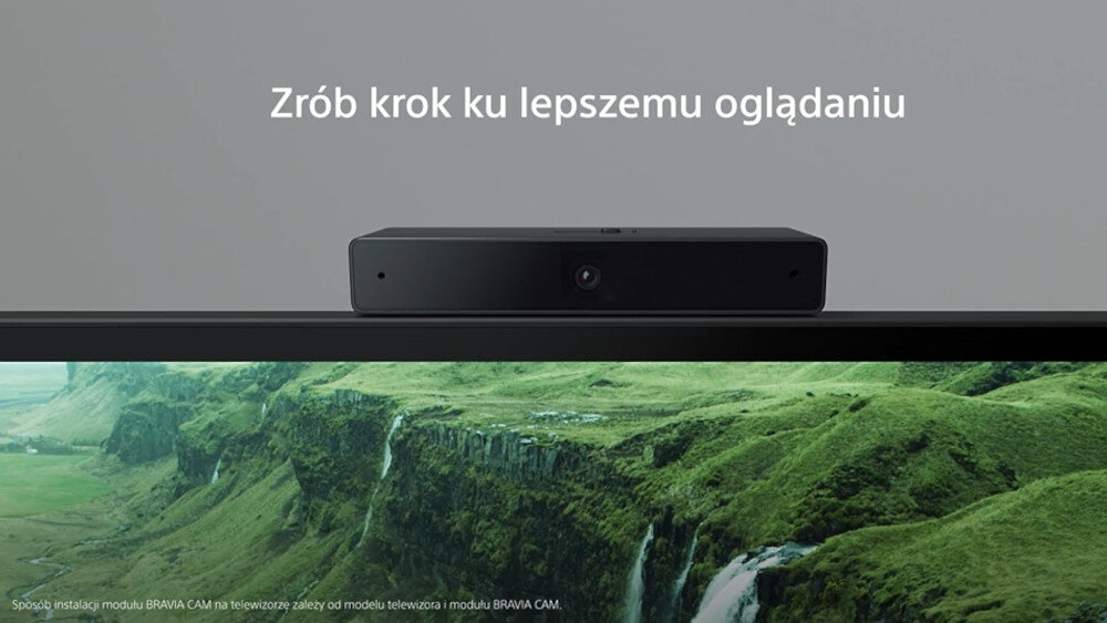 Na obrazie widoczny jest telewizor z wyświetlanym krajobrazem zielonych wzgórz i wodospadu. Nad ekranem znajduje się czarny moduł, a nad nim tekst: \'Zrób krok ku lepszemu oglądaniu\'.