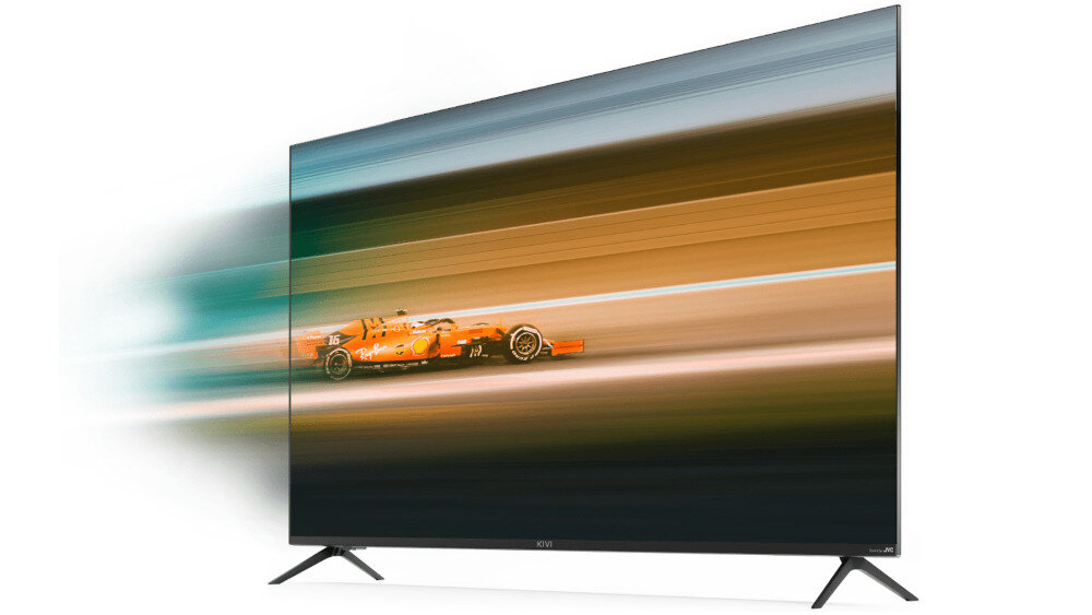 Telewizor z cienką ramką wyświetla dynamiczny obraz wyścigowego samochodu w ruchu. Na dolnej ramce widoczne jest logo \'KIVI\'.
