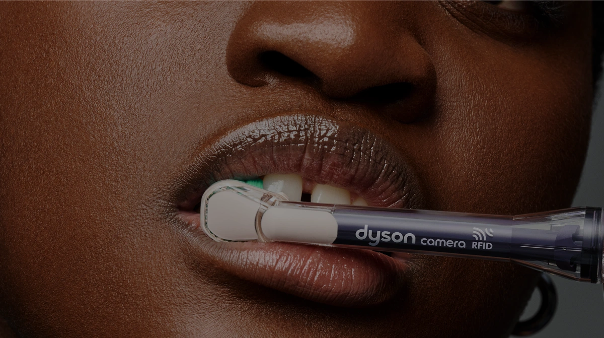Zbliżenie na kobiece usta i końcówkę Dyson Regular do szczoteczki Dyson CameraJet pokazane podczas mycia zębów