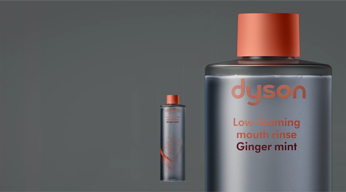Płyn do płukania jamy ustnej Dyson Ginger Mint w butelce z pomarańczową nakrętką. Obok ta sama butelka w powiększeniu