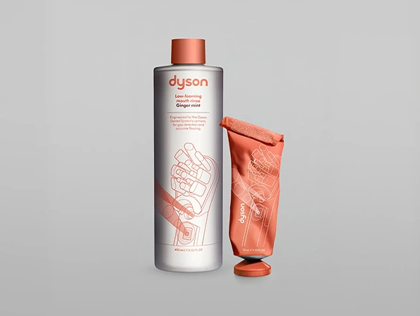 Płyn do płukania jamy ustnej Dyson Ginger Mint w butelce z pomarańczową nakrętką i pomarańczowa tubka pasty Dyson Ginger Mint