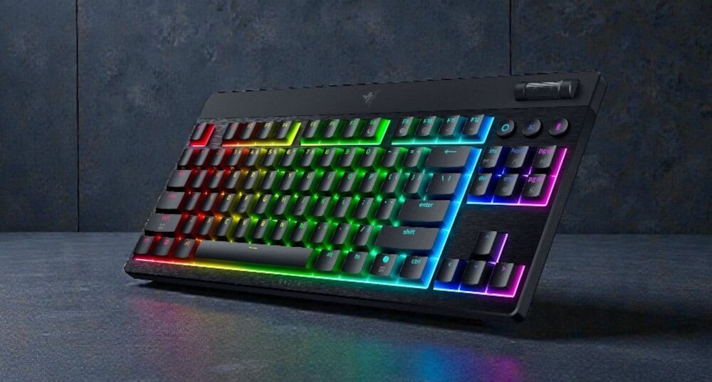 Klawiatura mechaniczna z podświetleniem RGB, widoczna na ciemnym tle. Na obudowie znajduje się logo producenta w kształcie trzech węży.