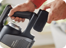 Osoba trzyma akumulator i odkurzacz z widocznym napisem \'PHILIPS AquaTrio 9000\'.