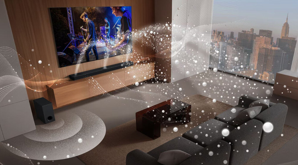 W nowoczesnym salonie znajduje się telewizor z wyświetlanym koncertem oraz soundbar umieszczony pod nim. Wokół rozchodzą się wizualizacje dźwięku, a za oknem widać panoramę miasta.