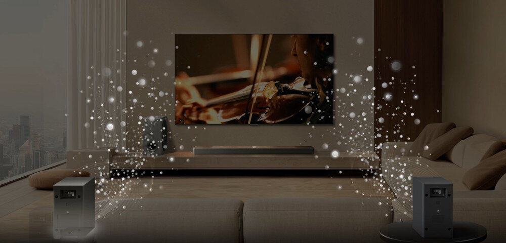 W eleganckim salonie znajduje się duży telewizor z wyświetlonym obrazem skrzypiec, a przed nim umieszczony jest soundbar. Wokół soundbara i dwóch głośników widoczne są efekty świetlne symbolizujące dźwięk przestrzenny.
