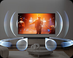 300x240 2 hw-b750f Obraz przedstawia nowoczesny salon z dużym telewizorem wyświetlającym koncert. Wokół telewizora widoczne są efekty świetlne, a na pierwszym planie znajduje się okrągły stolik z dekoracją.
