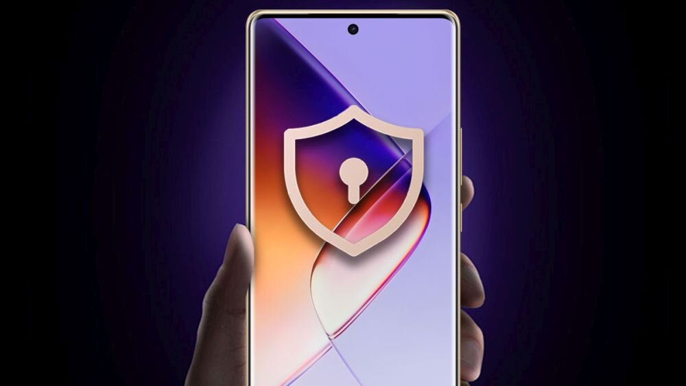 Osoba trzyma smartfon z wyświetlaczem w kolorach fioletu i pomarańczu, na którym widoczna jest ikona tarczy z kłódką. Obudowa telefonu jest złota.