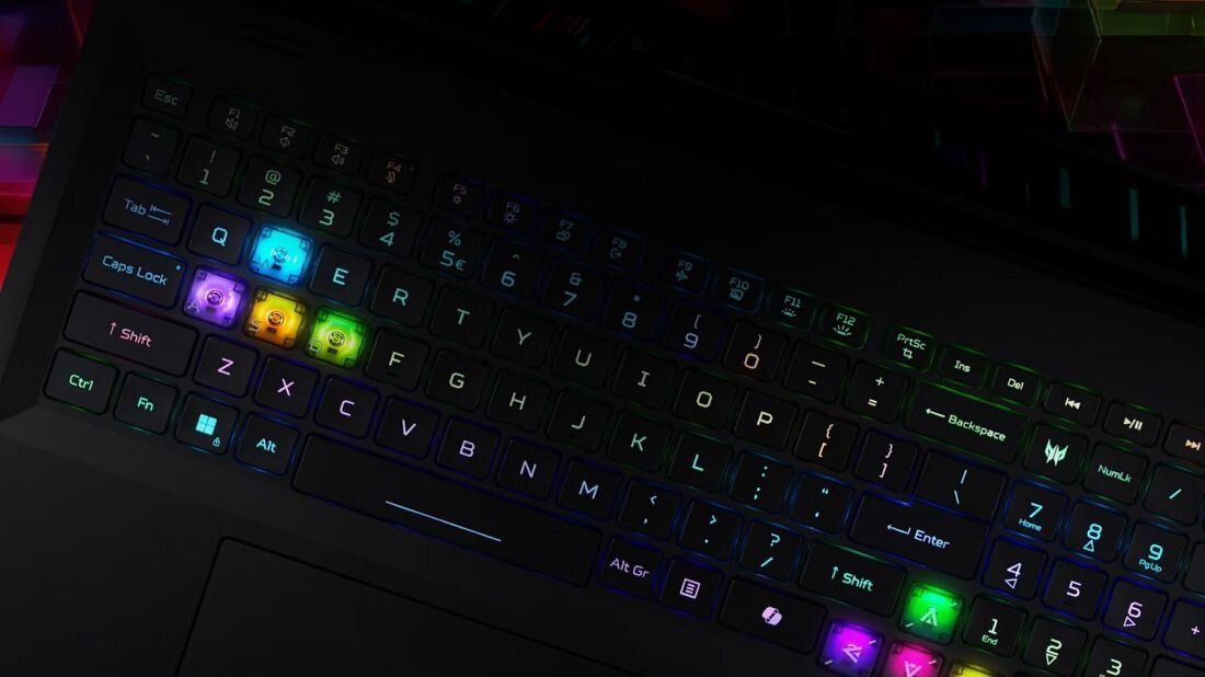 Klawiatura laptopa z podświetleniem RGB, gdzie niektóre klawisze świecą w różnych kolorach. Widoczne są klawisze z literami, cyframi oraz logo PREDATOR.
